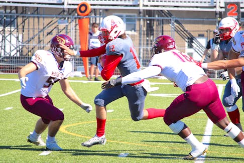 Acadia Axemen quarterback Dante Tabacu, centre, tries to split the Mount Allison Mounties defence Sept. 17 at Raymond Field in Wolfville.