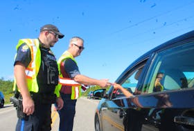 Const. Shaun MacLellan, left, stops traffic while MADD Cape Breton member Steve Gillespie hands out a red ribbon to a motorist on SPAR Road, Sydney Friday morning. The Project Red Ribbon education campaign promotes a safe and sober driving and boating over the long weekend. Gillespie was joined by MADD Cape Breton president Rob Matheson and other MADD Cape Breton members for Friday’s campaign. GREG MCNEIL/CAPE BRETON POST