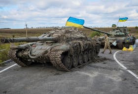 A Ukrainian serviceman walks near captured Russian tanks with installed Ukrainian flags, as Russia's attack on Ukraine continues, near the town of Izium, recently liberated by Ukrainian Armed Forces, in Kharkiv region, Ukraine, on Monday, Sept. 19, 2022. - Gleb Garanich / Reuters