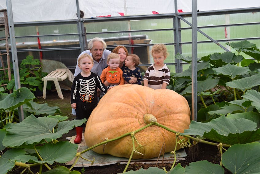 Tom Dudka poses for a picture with five of his grandchildren and the giant pumpkin he is growing this year. He estimates that the pumpkin already weighs more than 700 pounds.