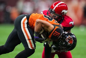 B.C. Lions' Bryan Burnham, front, is tackled by Calgary Stampeders' Brad Muhammad during the first half of CFL football game in Vancouver, on Saturday, September 24, 2022.