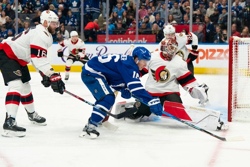  Maple Leafs winger Mitchell Marner tries to control the puck in front of Senators netminder Cam Talbot during the first period.