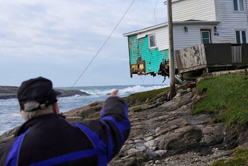  A person points towards a damaged house after the arrival of Hurricane Fiona in Port Aux Basques, Newfoundland.