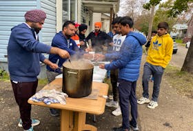 More than 600 people, most who were university students from India, made their way to a house on Havelock Street in Sydney where hot tea, warm food, water and socialization were on offer. Above, Meed Singh, left, stirs the pot while Yogesh Bansal ladles out a portion to Nirag Chaudhari while Sahil Batel, far right waits patiently. DAVID JALA/CAPE BRETON POST