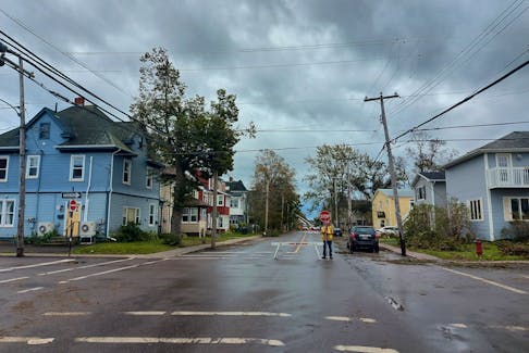 A flagger stops traffic on a Charlottetown street Sept. 27. Roads and streets are closed around the Island as crews clean up fallen trees and branches.