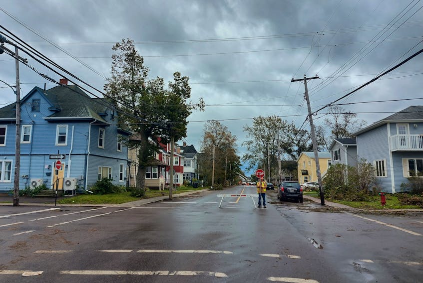 A flagger stops traffic on a Charlottetown street Sept. 27. Roads and streets are closed around the Island as crews clean up fallen trees and branches.