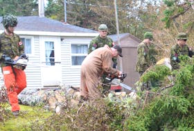 Military members help clear a felled tree near a power line in Catalone on Wednesday. IAN NATHANSON/CAPE BRETON POST