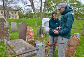 Parks Canada conservator Antoine Pelletier, right, and Parks Canada adviser Golnaz Karimi discuss gravestones at Garrison Graveyard at Fort Anne during a workshop on cleaning gravestones held in May.