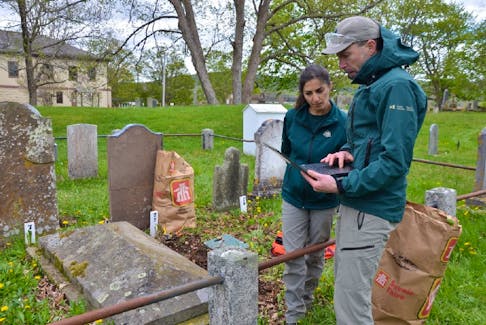 Parks Canada conservator Antoine Pelletier, right, and Parks Canada adviser Golnaz Karimi discuss gravestones at Garrison Graveyard at Fort Anne during a workshop on cleaning gravestones held in May.