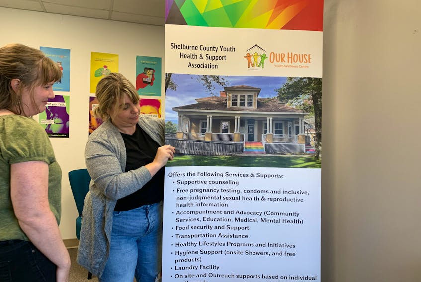 Our House youth outreach worker Melissa Strachan (left) and executive director Amy MacKinnon put up a banner at their new satellite office at the  Municipality of Barrington Administrative Centre. KATHY JOHNSON
