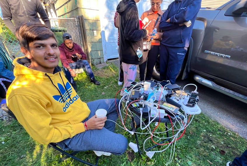 Sahib Batel watches over an octopus of mobile phone cords while the devices get a charge from a generator in north end Sydney. The power was provided by a generous neighbour of two Indian students who have been running a makeshift kitchen out of their yard since Saturday. DAVID JALA/CAPE BRETON POST