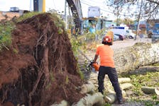 Crews from the cities of Moncton and Fredericton in New Brunswick work on removing a tree that had fallen on a house on Queen Street in Charlottetown on Sept. 29. Dave Stewart • The Guardian
