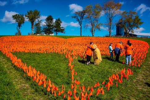 Geneva Maloney and Virginia Michael hug in the middle of a giant heart comprised of over 14,000 orange flags on the grounds of the former Shubenacadie Indian Residential School on Friday, Sept. 30, 2022. Hundreds of people took part in a ceremony marking Truth and Reconciliation Day on Friday.