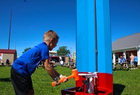 Lucca Kinch, 6, tries his hand at a strength tester on the second day of the Evangeline Area Agricultural Exhibition. - Kristin Gardiner