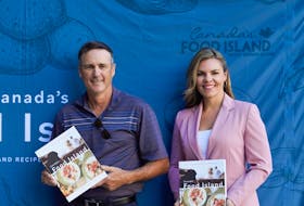 Minister of Fisheries and Communities Jamie Fox and marketing director of Lobster P.E.I. Charlotte Campbell stand with copies of Canada's Food Island: A Collection of Stories and Recipes from Prince Edward Island.