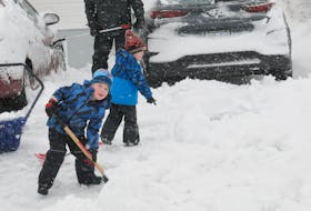 Brothers Jacob (left) and Noah Crant help shovel snow at their Mount Pearl home Saturday morning, Jan. 21. About 18 centimetres had fallen Friday night, with up to 40 more centimetres expected in some areas before Sunday morning.   -Photo by Joe Gibbons/The Telegram