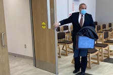 Sgt. Adrian Butler, an RCMP bloodstain pattern analyst, holds the door open as he leaves Nova Scotia Supreme Court in Dartmouth on Wednesday after testifying at William Michael Sandeson's first-degree murder trial.