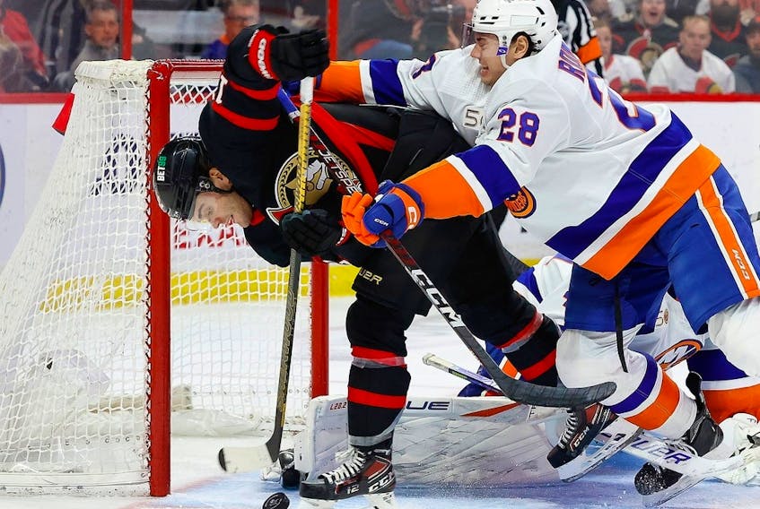  Ottawa Senators right wing Alex DeBrincat battles with New York Islanders defenceman Alexander Romanov (28) for a loose puck during the third period.