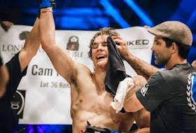 Cameron Nelson, left, gets his hand raised in victory after defeating his opponent, Michael William Adams, by a triangle choke in the third round of their amateur welterweight bout at Fight League Atlantic’s FLA5 event in October 2022 at the Pictou Wellness Center in New Glasgow, N.S. Celebrating with Nelson is head coach Matt MacGrath. Contributed