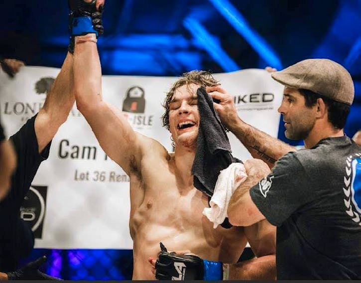 Cameron Nelson, left, gets his hand raised in victory after defeating his opponent, Michael William Adams, by a triangle choke in the third round of their amateur welterweight bout at Fight League Atlantic’s FLA5 event in October 2022 at the Pictou Wellness Center in New Glasgow, N.S. Celebrating with Nelson is head coach Matt MacGrath. Contributed