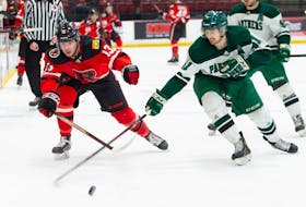 UNB Red Cody Morgan battles UPEI’s Conor MacEachern for possession of the puck during the game in Fredricton on Saturday, Jan. 7.