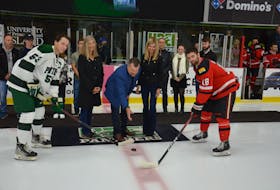 A banner-raising ceremony honouring Billy MacMillan’s contributions as a player at Saint Dunstan’s University and as a coach with the UPEI Panthers took place at MacLauchlan Arena in Charlottetown before an Atlantic University Sport (AUS) Men’s Hockey Conference game between UPEI and UNB on Oct. 7. MacMillan’s son, John, drops the puck for the opening faceoff between UPEI captain Kurtis Henry, left, and UNB captain Jason Wilms, right. Also taking part in the ceremonial faceoff are MacMillan’s daughters, Anne Morgan, second left, and Susan MacMillan, second right. Jason Simmonds • The Guardian