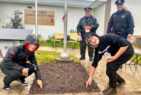 Kallie Paul, from left, and Raine Mulley, students at Maupeltuewey Kina’matno’kuom School in Membertou, planted red tulips Tuesday at Red Dress Park outside the Cape Breton Regional Police station in Membertou as Const. Roddy Christmas and Sgt. Barry Gordon looked on. “This feels pretty cool to be able to be part of this,” said Mulley, 12. Chris Connors/Cape Breton Post