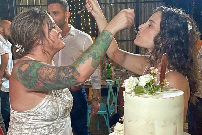 Jess Burke, left, and Shani Gil feed each other wedding cake after their marriage ceremony just outside Tel Aviv, Israel. - Courtesy of Clancy McDaniel