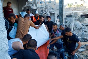 Palestinians carry the dead body of a woman killed in Israeli strikes in Khan Younis, in the southern Gaza Strip, October 12, 2023. REUTERS/Ibraheem Abu Mustafa