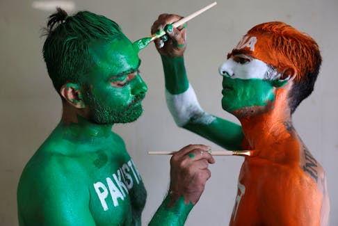 Cricket fans, Arun Haryani (Right) and Anil Advani (Left) paint their bodies in the Indian and Pakistani national flag colours, ahead of the match between India and Pakistan in the ICC World Cup, in Ahmedabad, India, October 11, 2023. REUTERS/Amit Dave