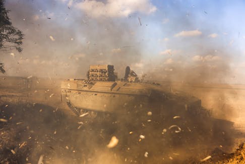 An Israeli Armoured Personnel Carrier (APC) is obscured as it whips up dust near Israel's border with the Gaza Strip, in southern Israel October 15, 2023. REUTERS/Ronen Zvulun