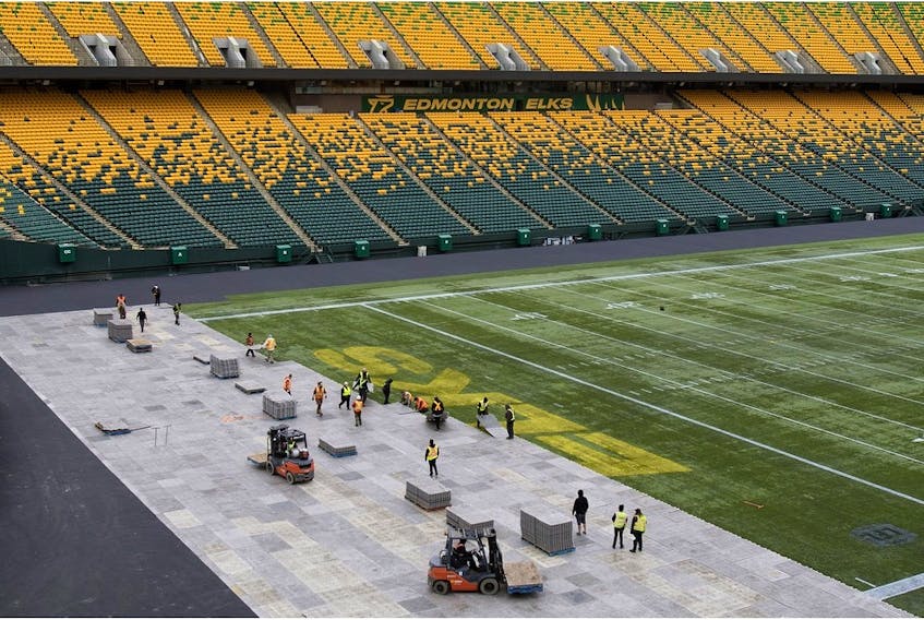 Crews lay down plastic flooring on Tuesday Oct. 17, 2023, as they begin the process of creating an outdoor hockey rink at Commonwealth Stadium for the Heritage Classic.