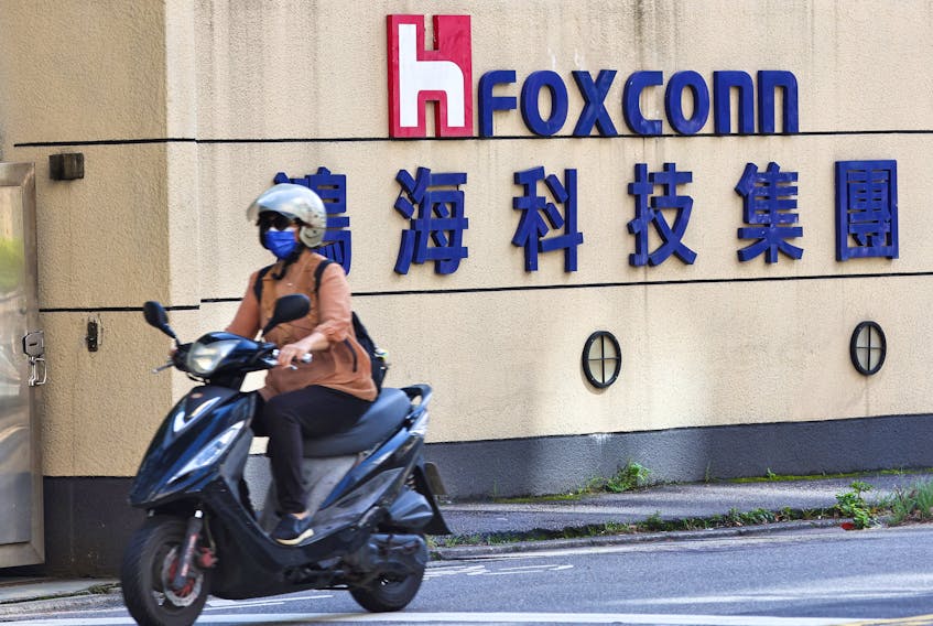 A woman drives past the logo of Foxconn outside the company's building in Taipei, Taiwan November 9, 2022.