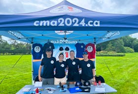 Summer students staff an information booth about the 2024 Congrès mondial acadien (CMA) at a community event this past summer. Contributed