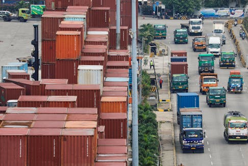 Trucks drive past stacks of containers at the Tanjung Priok port in Jakarta, Indonesia, February 3, 2023.