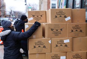 Ellie Amador picks up a United States Department of Agriculture (USDA) Farmers to Families food box as food is distributed at the nonprofit New Life Centers' food pantry in Chicago, Illinois, U.S. March 16, 2021.
