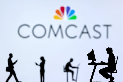 Small toy figures with laptops and smartphones are seen in front of displayed Comcast logo, in this illustration taken December 5, 2021.
