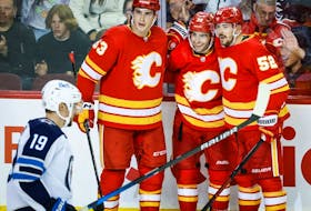 Calgary Flames Matthew Coronato, centre right, celebrates his goal with Adam Ruzicka, centre left, and defenceman MacKenzie Weegar as Winnipeg Jets forward David Gustafsson skates past at Scotiabank Saddledome in Calgary on Monday, Oct. 2, 2023.