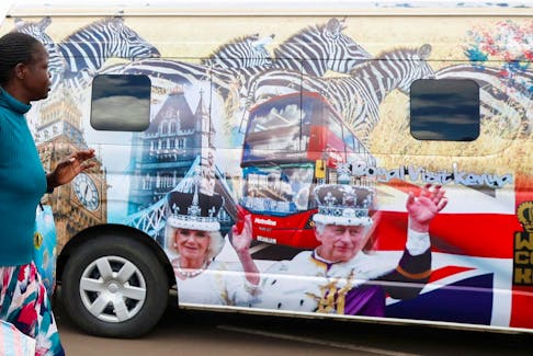 A woman gestures as she walks past a British High Commission (BHC) courtesy van decorated with images of Britain's King Charles and Queen Camilla ahead of their state visit, at the Green Park bus terminus in Nairobi, Kenya October 27, 2023.
