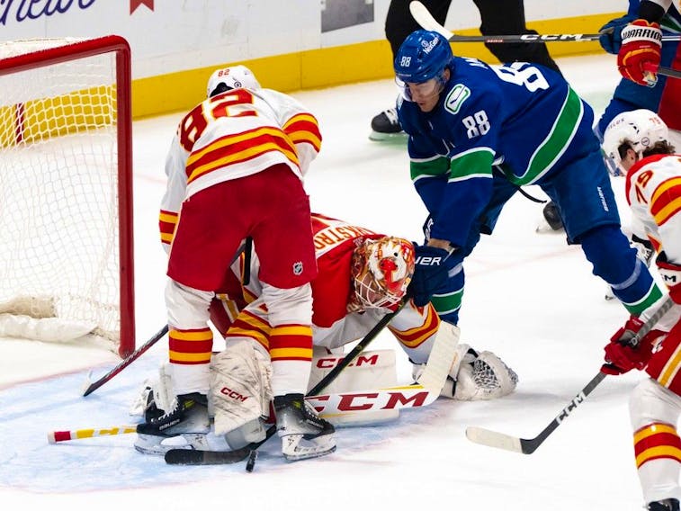 Calgary Flames goalie Jacob Markstrom, centre, covers the puck as