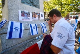 Patel Jelovdovski, a former member of the Israel Defense Forces (IDF), becomes emotional as he lights a candle for his cousin, Alexei Shmakalov, an IDF soldier who was killed Sunday while responding to the attack in Sderot, Israel, prior to the start of a rally to support Israel at Victoria Park in Halifax on Monday, Oct. 9, 2023.
