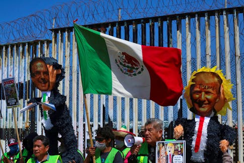 Migrants hold up pinatas with pictures of Mexican Foreign Minister Marcelo Ebrard and former U.S. President Donald Trump during a protest at the border fence in Playas Tijuana to demand the U.S. government to lift a public health order known as Title 42, a COVID-era policy that allows the expulsion of migrants to prevent the spread of the virus, in Tijuana, Mexico April 29, 2022.