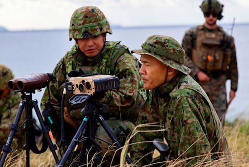 Soldiers of Japanese Ground Self-Defense Force's (JGSDF) Amphibious Rapid Deployment Brigade (ARDB), Japan's first marine unit since World War Two, take part in a military drill as a U.S. Marine personnel looks on, at an uninhabited Irisuna island close to Okinawa, Japan, November 15, 2023.