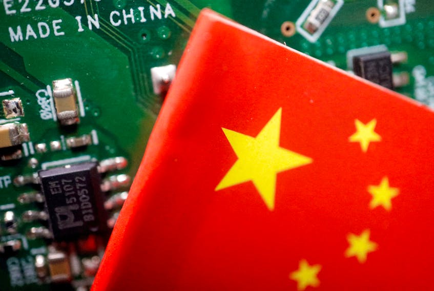 A Chinese flag is displayed next to a "Made in China" sign seen on a printed circuit board with semiconductor chips, in this illustration picture taken February 17, 2023.
