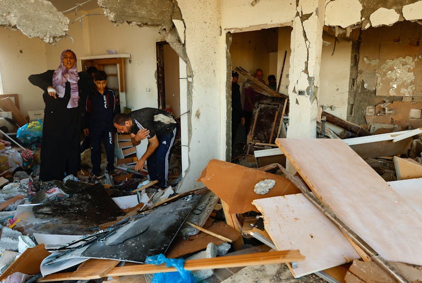 People inspect the damage at the site of an Israeli strike on the apartment building, amid the ongoing conflict between Israel and Palestinian Islamist group Hamas, in Khan Younis in the southern Gaza Strip November 18, 2023.