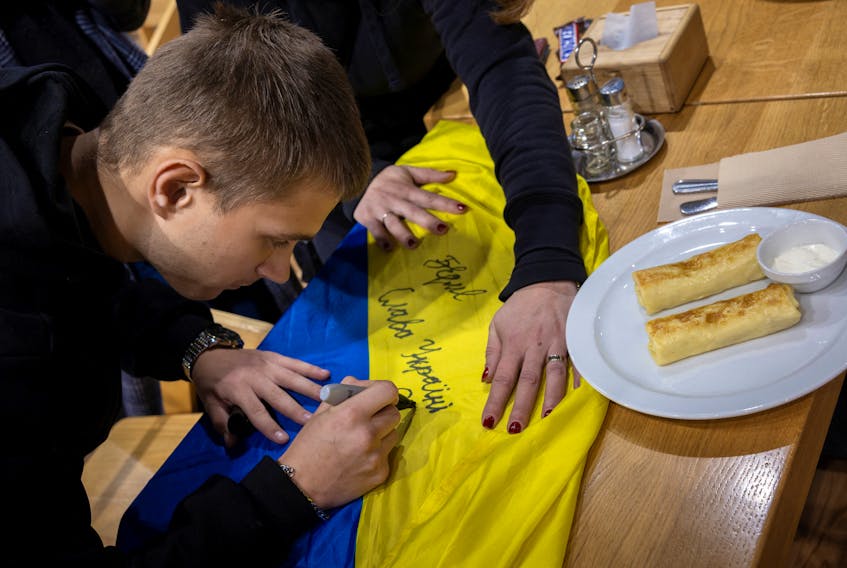 Bohdan Yermokhin, a Ukrainian teenager who was taken to Russia from the occupied city of Mariupol, signs the Ukrainian flag after arriving in his home country from Belarus at a rest stop in Rivne, amid Russia's ongoing attack on Ukraine, November 19, 2023.