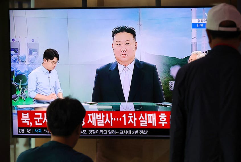Passengers watch a TV broadcasting a news report on North Korea firing a space rocket, at a railway station in Seoul, South Korea, August 24, 2023.   