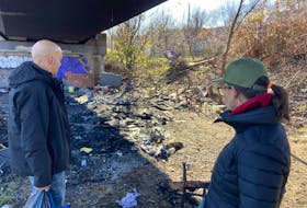 A fiery explosion destroyed part of homeless encampment near the Angus L. Macdonald Bridge in Halifax on Tuesday morning. A man who lost his tent in the fire is shown looking at the carnage. A woman who lives nearby showed up with chicken soup for people living in the encampment that borders Barrington Street.