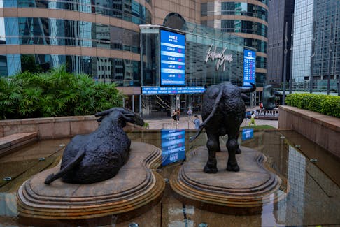 Bull statues are placed in font of screens showing the Hang Seng stock index and stock prices outside Exchange Square, in Hong Kong, China, August 18, 2023.