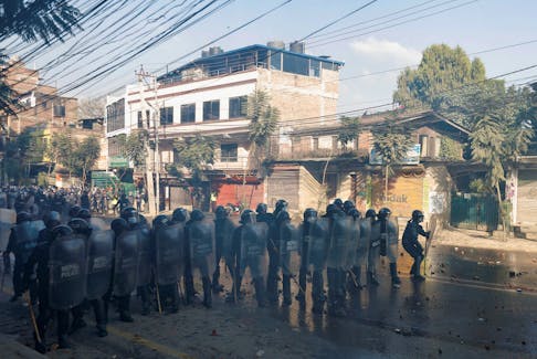 Riot police personnel take cover as they clash with Pro-monarchist protesters during their protest demanding the restoration of Nepal's monarchy, which was abolished in 2008, saying the governments have failed to make any significant changes in Kathmandu, Nepal November 23, 2023.